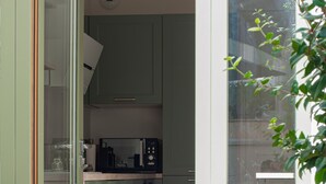 A narrow kitchen with green cabinets, a microwave, and a window.