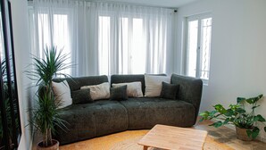 A living room with a dark green sofa, a wooden coffee table, and two potted plants.