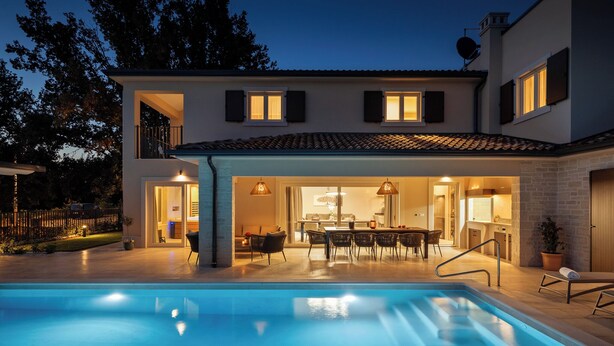 A modern house with a swimming pool, outdoor dining area, and a well-lit interior. - Luxury villa for 8 persons with swimming pool, whirlpool and sauna (Nova Vas)