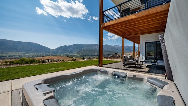 A hot tub with a mountain view, a deck with outdoor furniture, and a covered area with a balcony. - Mountain View Retreat B11|Hot Tub |Near Powder Mtn (Eden)
