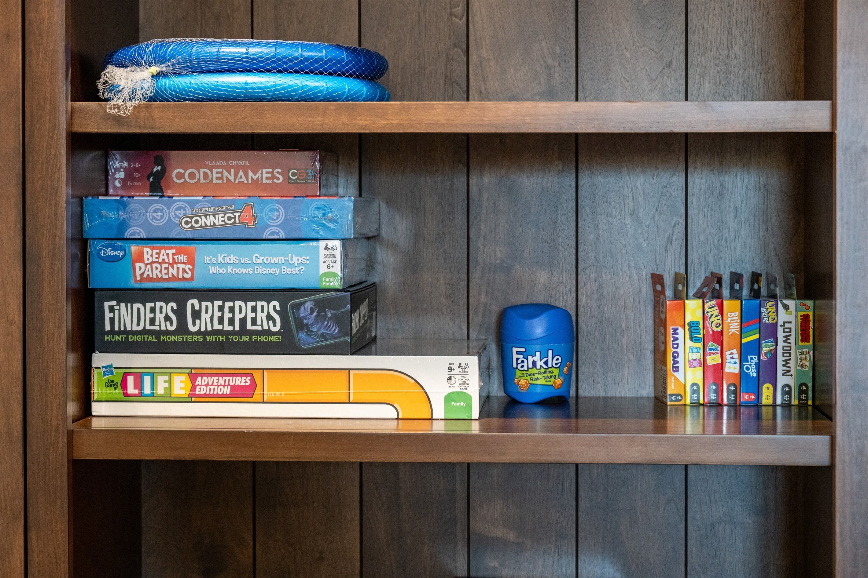 A wooden shelf with various board games and a blue toy.