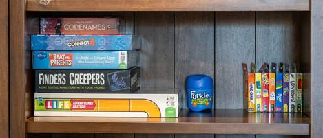 A wooden shelf with various board games and a blue toy.
