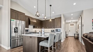 A modern kitchen with stainless steel appliances, a central island, and bar stools. - Mountain View Retreat B11|Hot Tub |Near Powder Mtn (Eden)