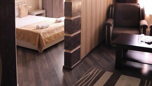 Una habitación de hotel moderna con cama, zona de estar y estantería empotrada.