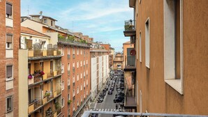 A narrow urban street flanked by multi-story buildings with balconies, a clear sky, and parked cars. - Bologna city center view by Wonderful Italy (Bologna)