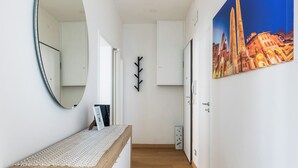 A hallway with a wooden bench, a mirror, a coat rack, and a door with a painting of a cityscape. - Bologna city center view by Wonderful Italy (Bologna)