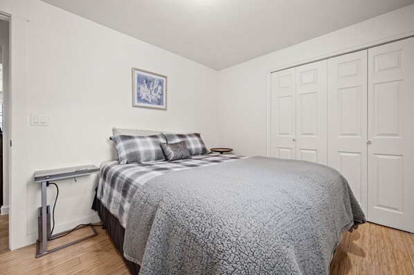 A bedroom with a bed, a desk, and a wardrobe.
