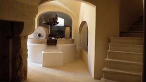 A stone-walled room with a stone bench, a stone table with a bowl, and a staircase. - Masseria Monet (Monopoli)