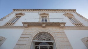 A building with a symmetrical facade, arched windows, and a central balcony with a decorative balustrade. - Masseria Monet (Monopoli)