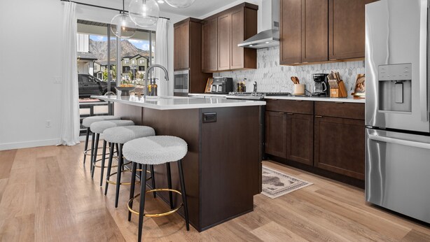 Une cuisine moderne avec des meubles en bois, des appareils en acier inoxydable et un îlot central doté de tabourets de bar.