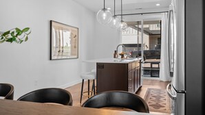 Une cuisine moderne dotée d’un îlot central, de luminaires suspendus et donnant sur la salle à manger.