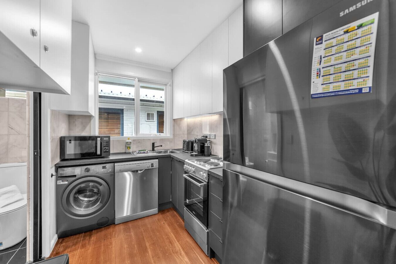 Una cocina moderna con electrodomésticos de acero inoxidable, lavadora y refrigerador.