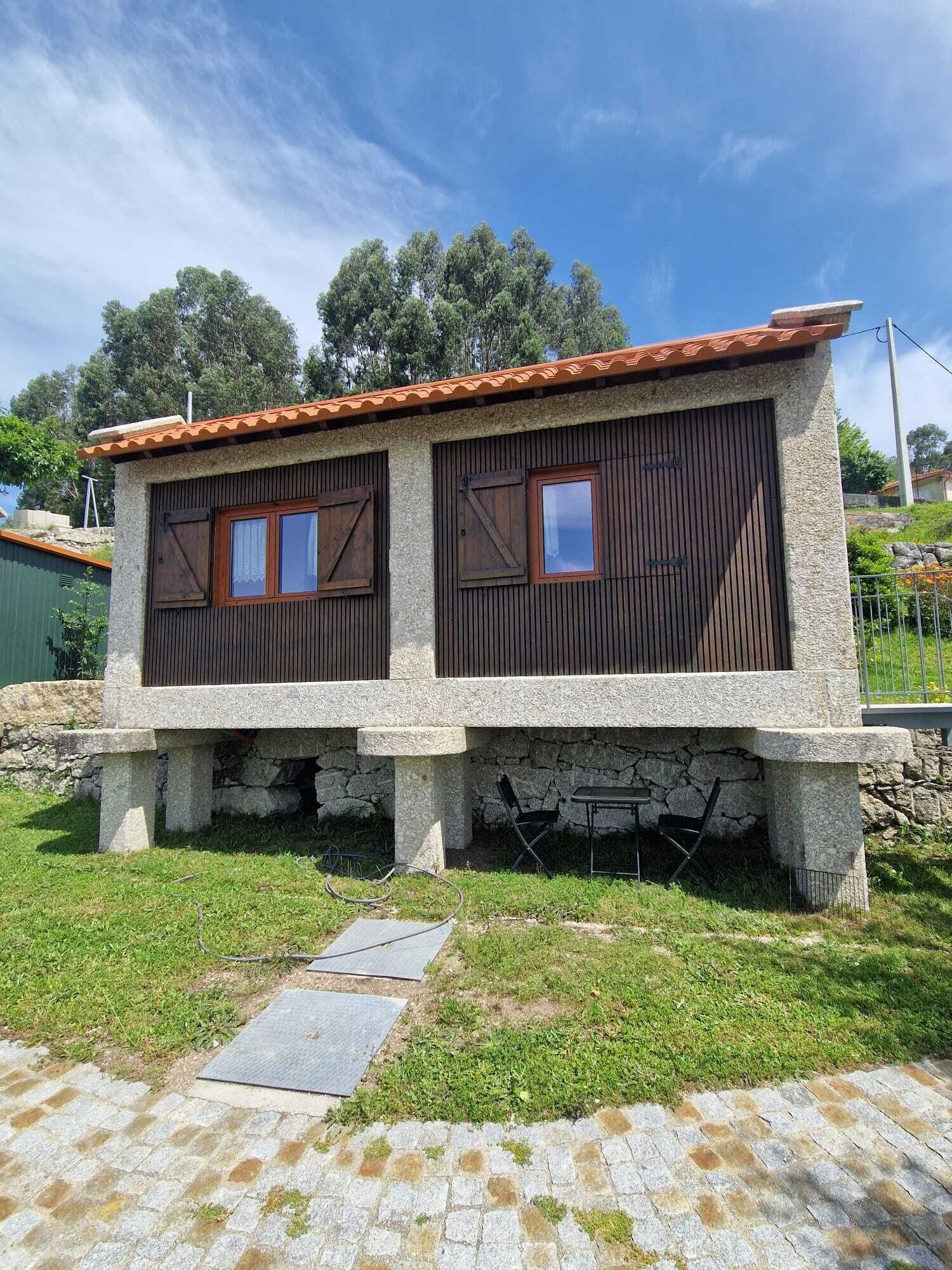 Un edificio de piedra con techo de tejas, dos ventanas de madera y base de piedra.
