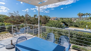 A balcony with a table and chairs, a pool, and a view of the surrounding landscape.