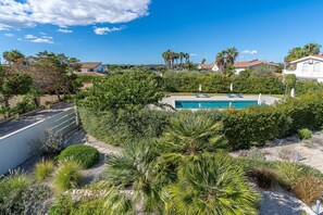 A swimming pool surrounded by lush greenery and houses in the background.