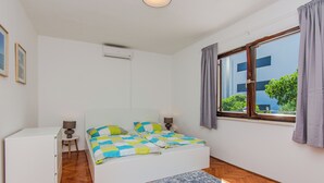 A bedroom with a bed, a desk, and a window with curtains. - Holiday home Kurta  (Privlaka)