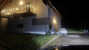 Ein zweistöckiges Haus mit Balkon, Auffahrt und kleinem Garten.