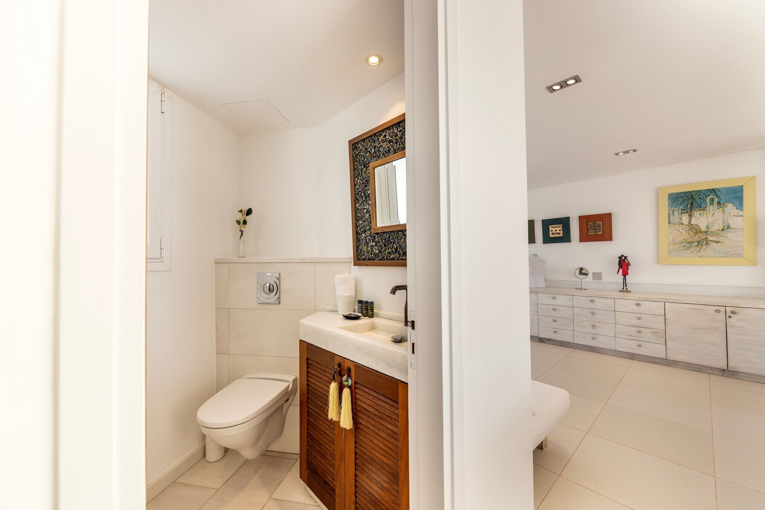 A modern bathroom with a toilet, sink, and wooden cabinet.
