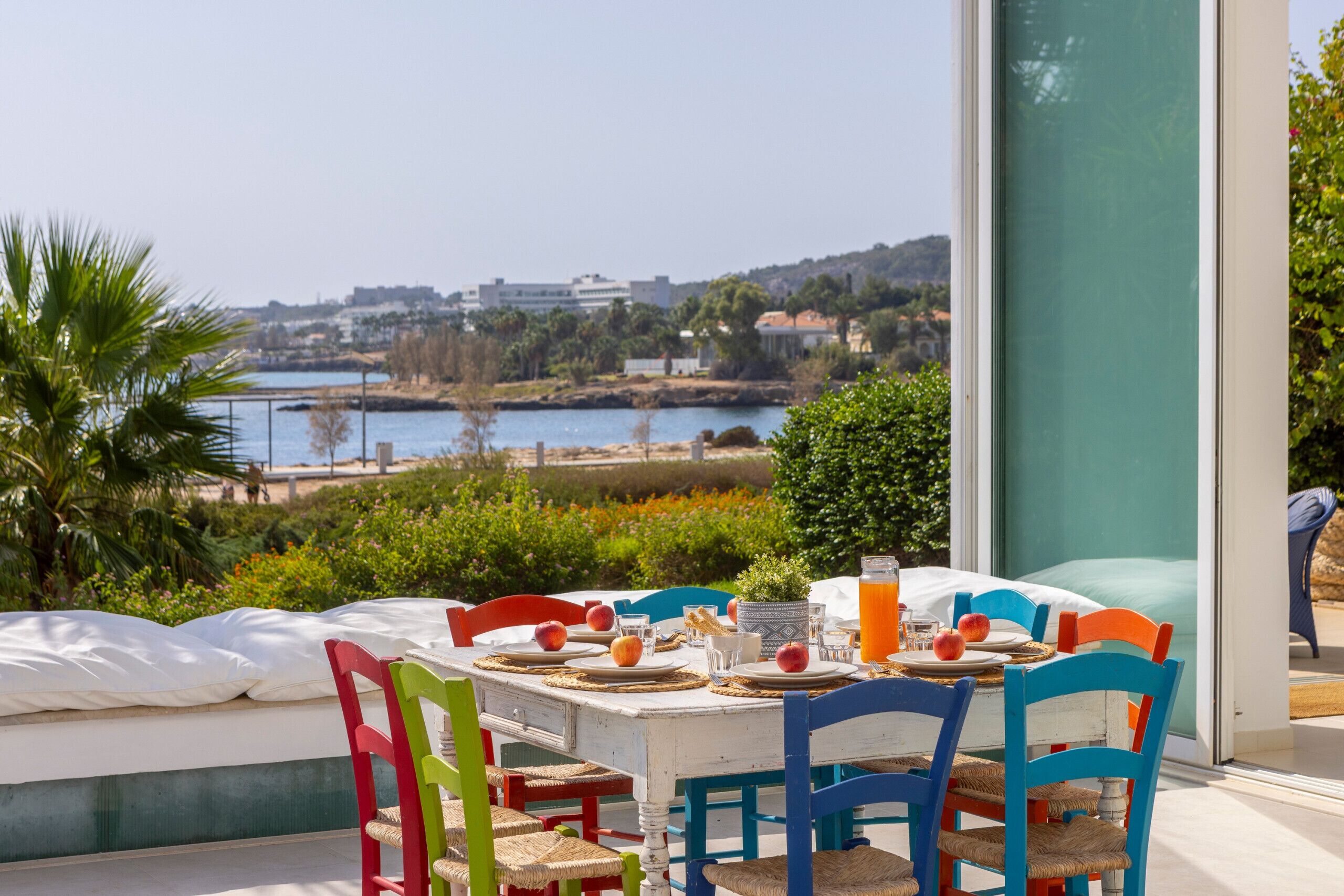 Uma área de refeições com mesa posta para dois, com vista para a paisagem de um corpo d'água e edifícios.