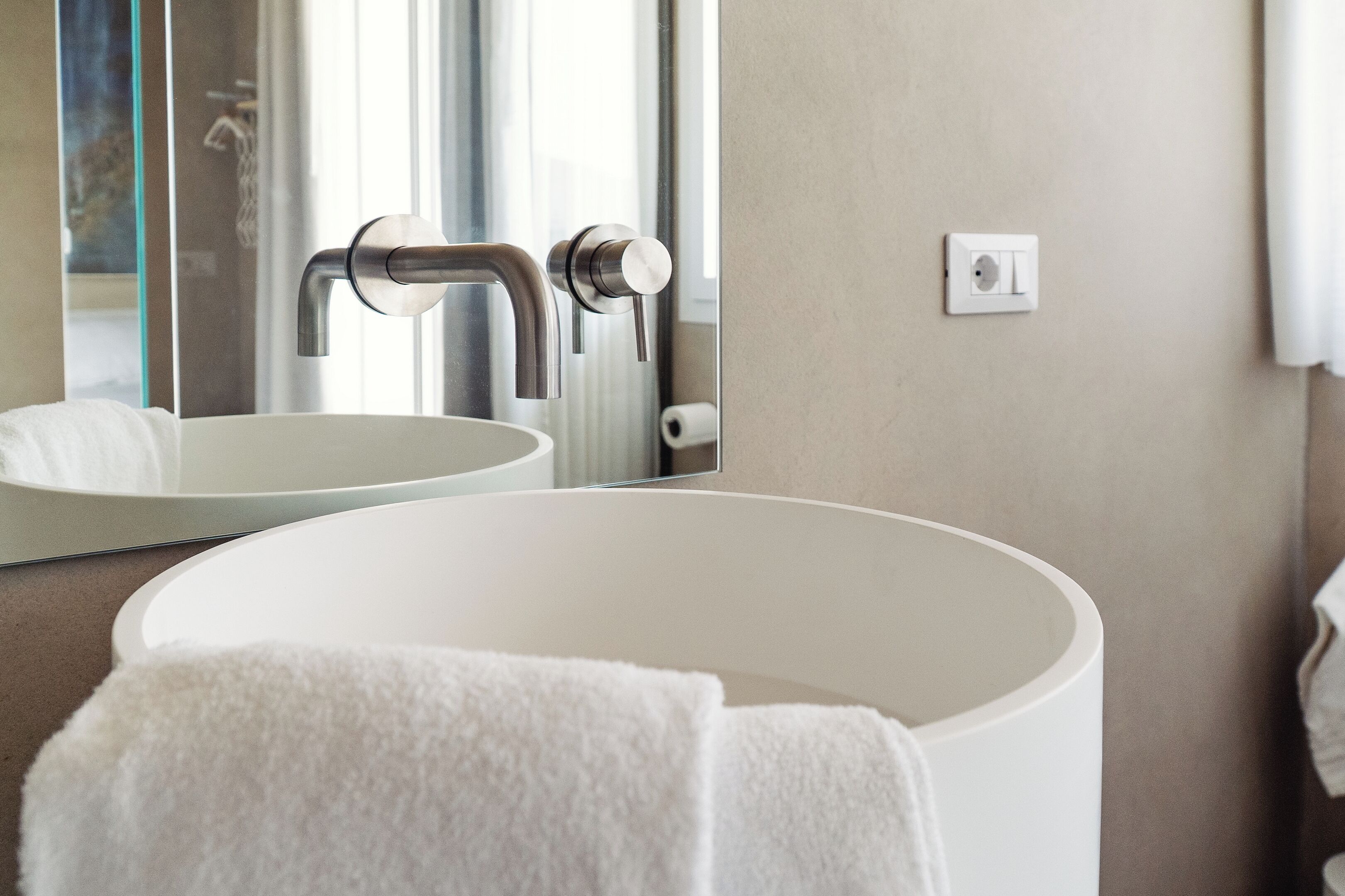 Une salle de bain avec un lavabo blanc, un miroir et une serviette.