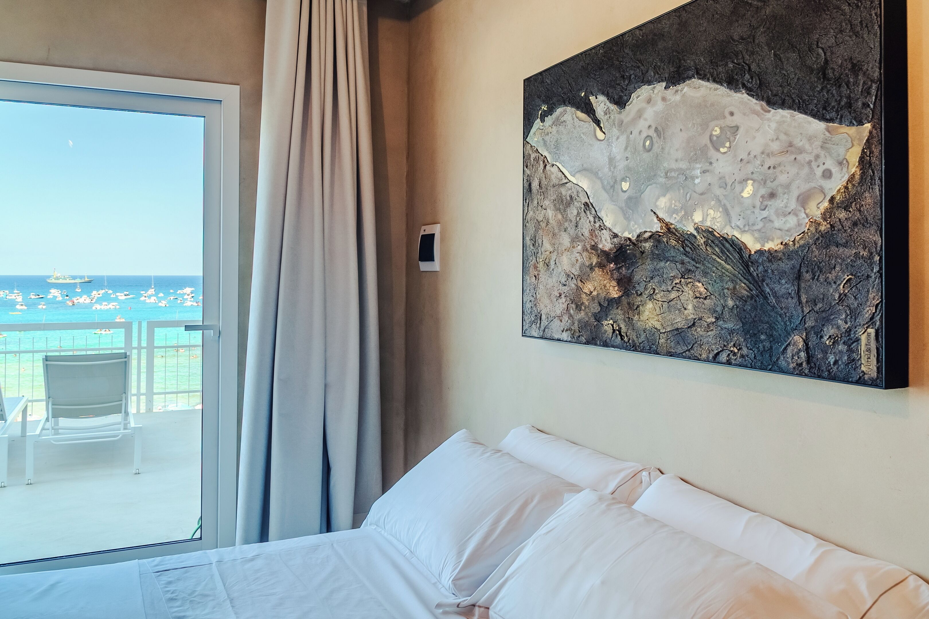 Ein Hotelzimmer mit großem Fenster und Balkon mit Stühlen sowie Blick auf das Meer.