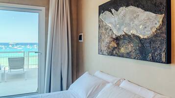 Ein Hotelzimmer mit großem Fenster und Balkon mit Stühlen sowie Blick auf das Meer.