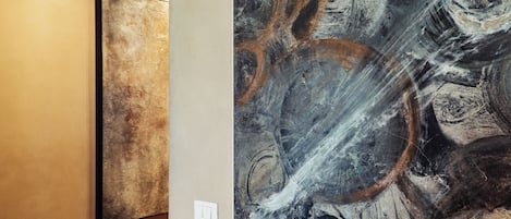 A wall with two artworks, one abstract and one with swirling patterns.
