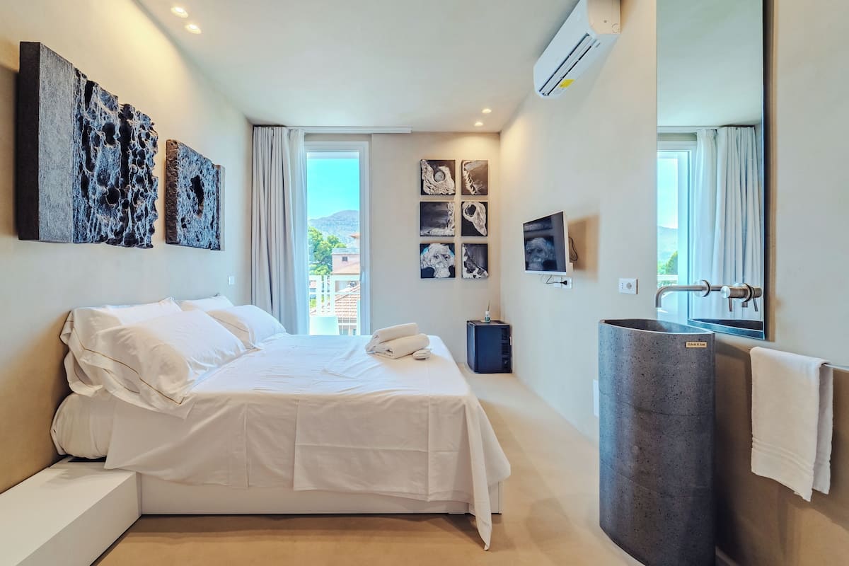 Een moderne hotelkamer met een groot bed, een ingebouwd wastafelmeubel en kunstwerken aan de muren.