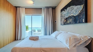 A hotel room with a large bed, a painting on the wall, and a view of the sea through the window. - Hybrid Icon Rooms Gallery (Palermo)