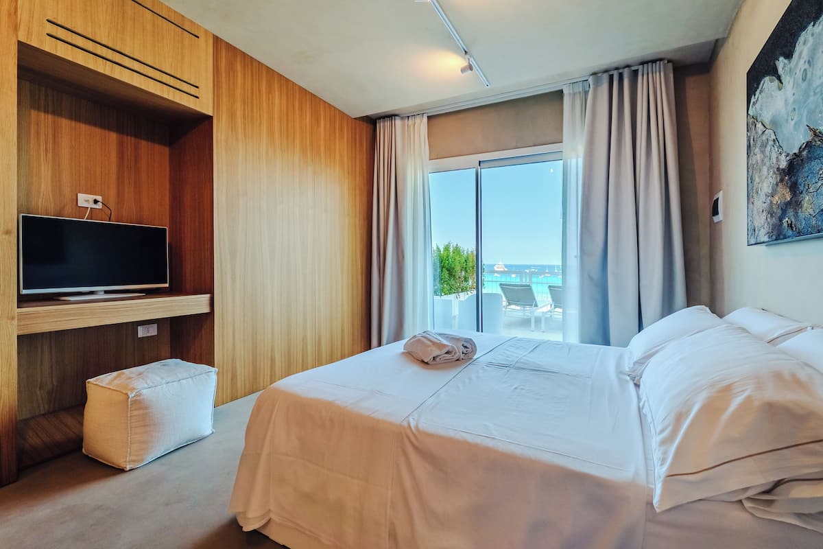 Een hotelkamer met een groot bed, een flatscreen-tv, een klein zithoekje en uitzicht op de omgeving.