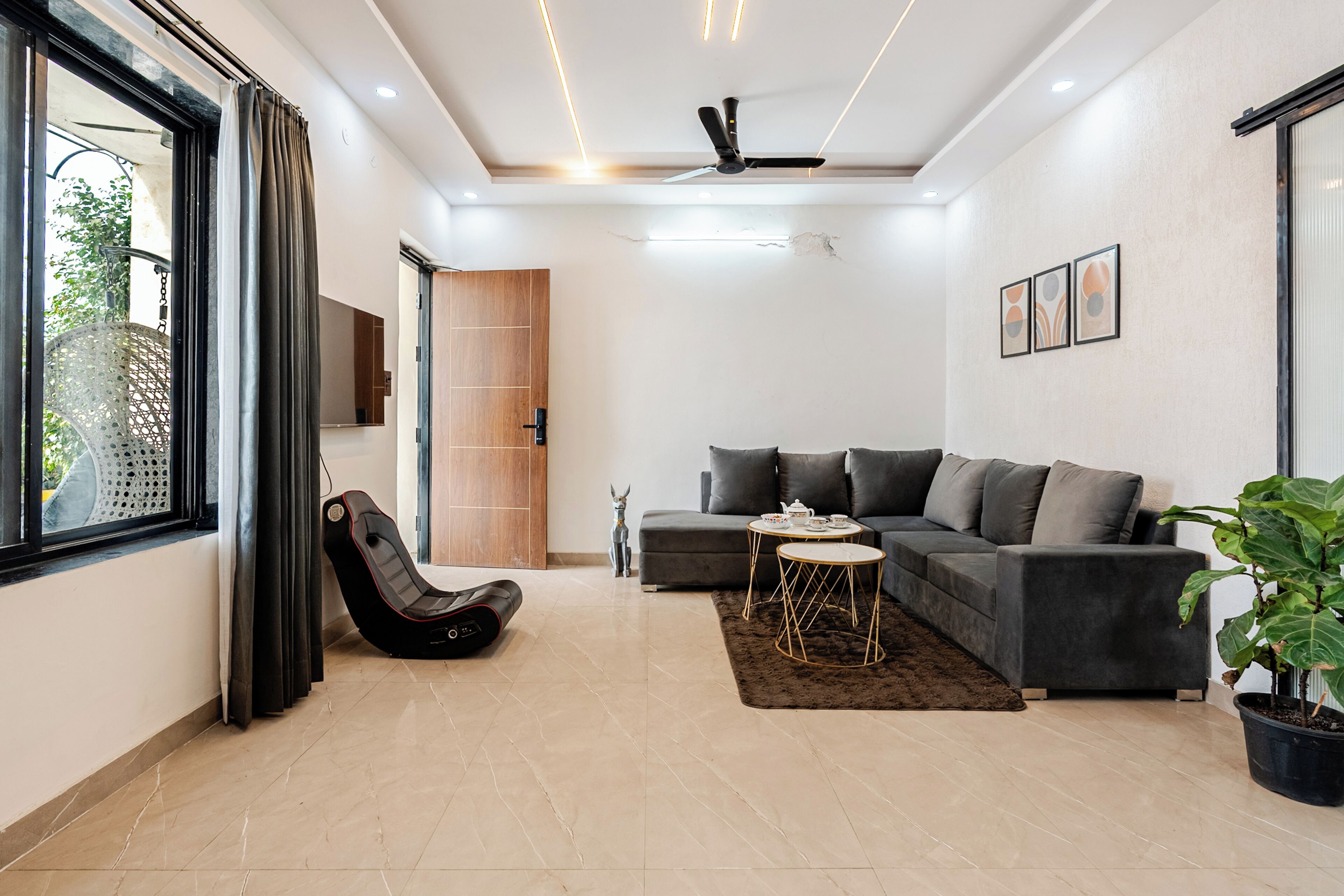 A modern living room with a sofa, a coffee table, a chair, a ceiling fan, and a potted plant.