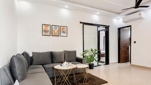 A modern living room with a grey sofa, two round tables with gold legs, a brown rug, and a ceiling fan.
