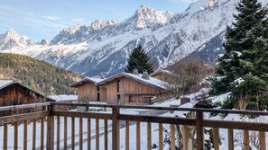 Eine Holzhütte mit einem Balkon mit Blick auf eine verschneite Berglandschaft.