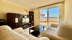 A living room with a sofa, a TV, a cabinet, and a balcony with a view. - Nice Apartment With Shared Pool (Roquetas de Mar)