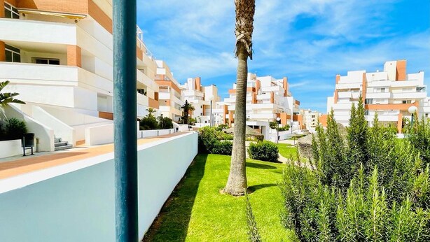 A modern residential building with balconies, a well-maintained lawn, and a clear sky. - Nice Apartment With Shared Pool (Roquetas de Mar)
