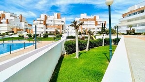 A modern residential complex with a swimming pool, green lawns, and a clear blue sky. - Nice Apartment With Shared Pool (Roquetas de Mar)