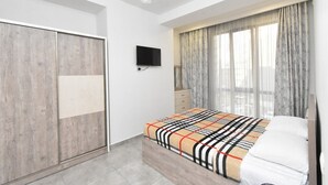 A bedroom with a bed, a wardrobe, a television, and a window with curtains. - Apartment by Luxe Group DI412 (Yerevan)