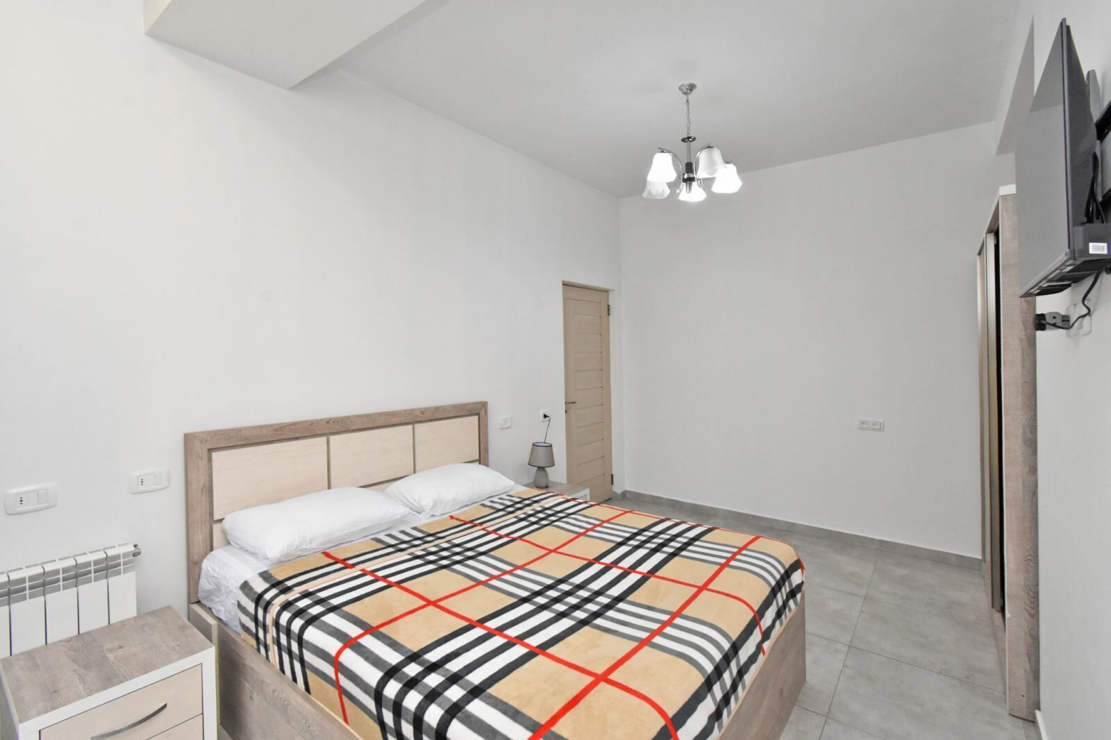Ein Schlafzimmer mit Bett, Nachttisch und Deckenleuchte.