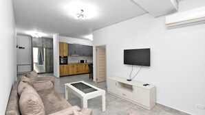 A modern living room with a sofa, coffee table, and TV. - Apartment by Luxe Group DI412 (Yerevan)
