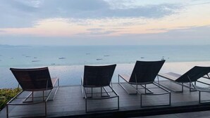 Eine Terrasse mit Liegestühlen mit Blick auf ein Gewässer und Boote.