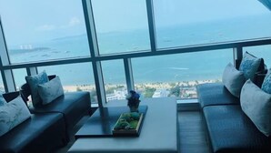 Ein Zimmer mit großem Fenster und Meerblick, ausgestattet mit einer Couch und einem kleinen Tisch mit einer Dekoration.