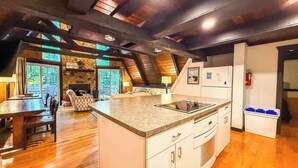 Une cuisine spacieuse dotée d’un îlot central, de planchers en bois et d’un mur d’accent en pierre.