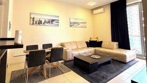 A modern living room with a sofa, coffee table, and dining area. - CEMELDA (Budva)