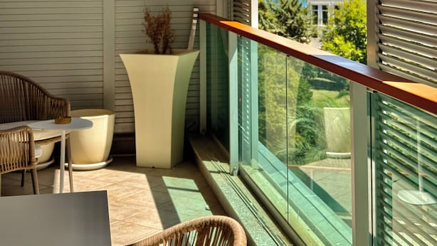 A balcony with a view of a lake and mountains, furnished with wicker chairs and a table. - CEMELDA (Budva)