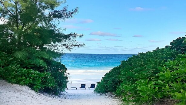 A beach path leading to three beach chairs on a sandy beach with a clear view of the ocean. - Charming Tickled Pink 2BR, 3BD, 3BTH home, minutes from pink sand beach (Harbour Island)