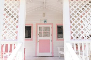 A white building with pink accents, a door, and windows. - Charming Tickled Pink 2BR, 3BD, 3BTH home, minutes from pink sand beach (Harbour Island)