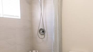 Une salle de bain avec douche, toilettes et carrelage au sol à motifs.
