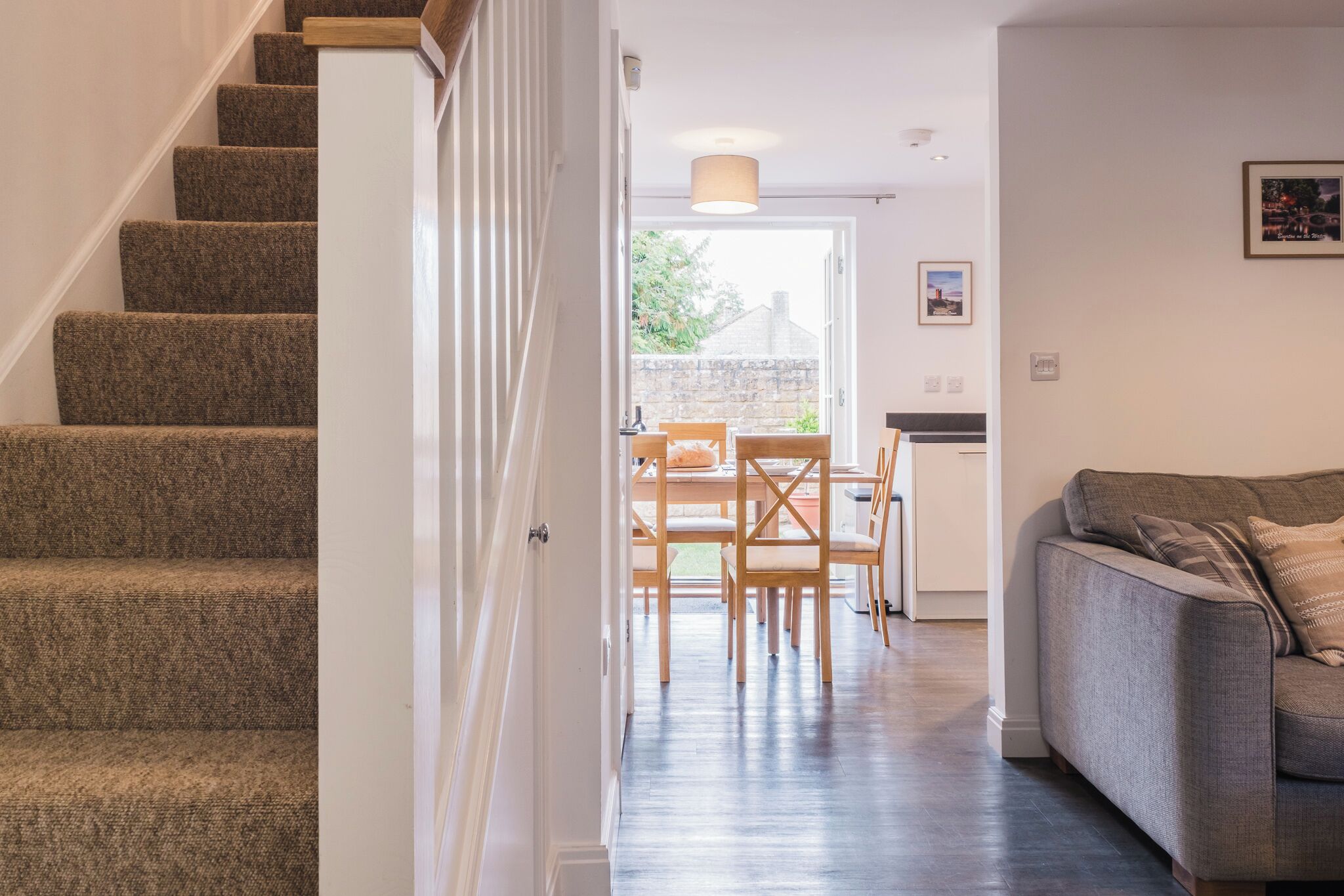 A staircase leading to a dining area with a table and chairs, a sofa, and a view of the outdoors.