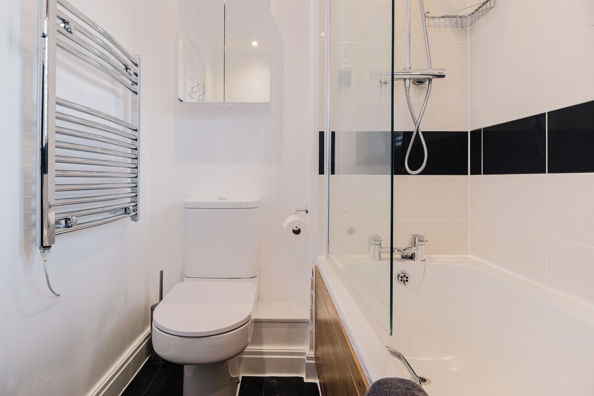 A modern bathroom with a toilet, a glass-enclosed shower, and a bathtub.