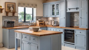 A modern kitchen with light blue cabinets, a wooden island, and a brick backsplash.